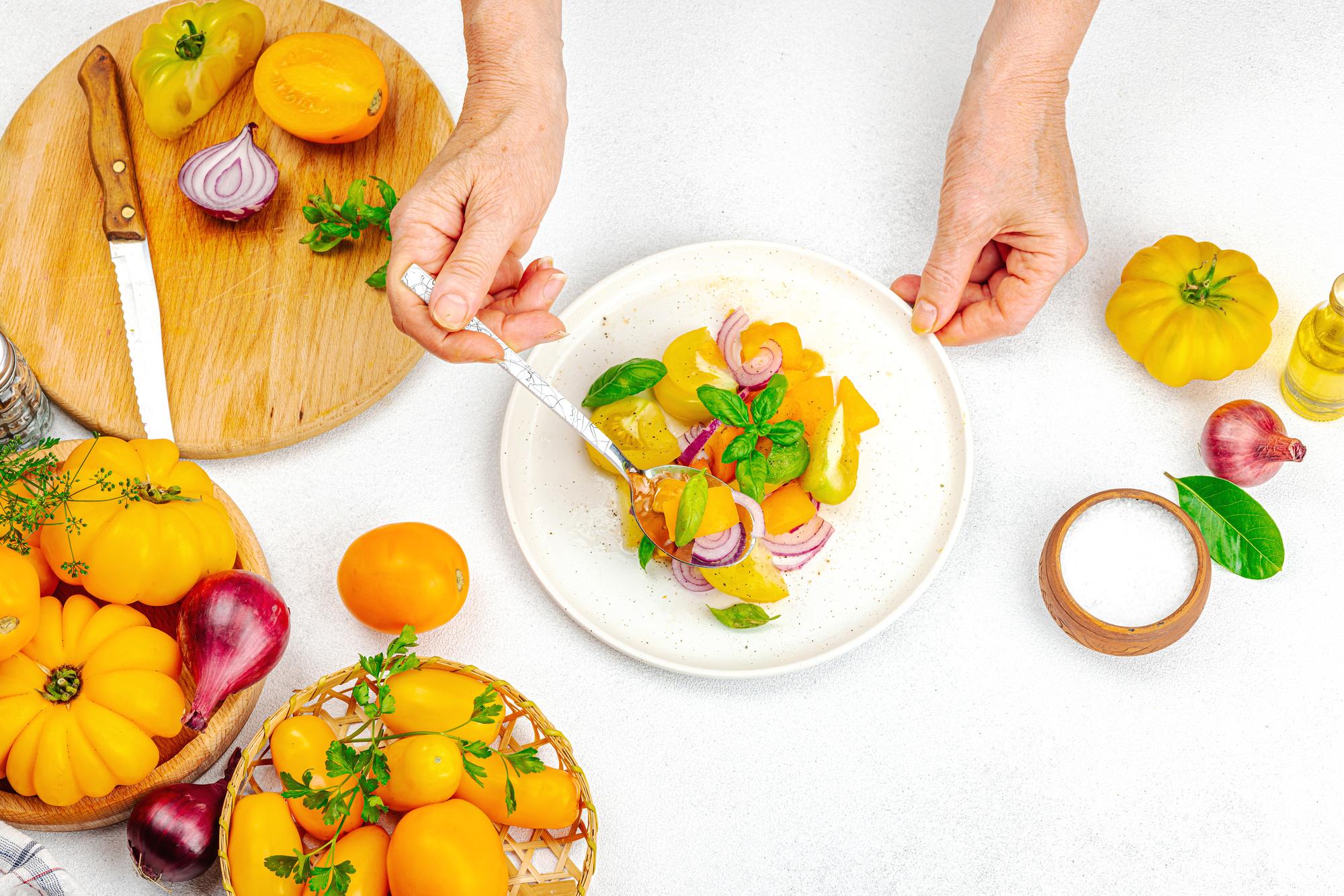 hands plating a composed seasonal dish in a bright kitchen